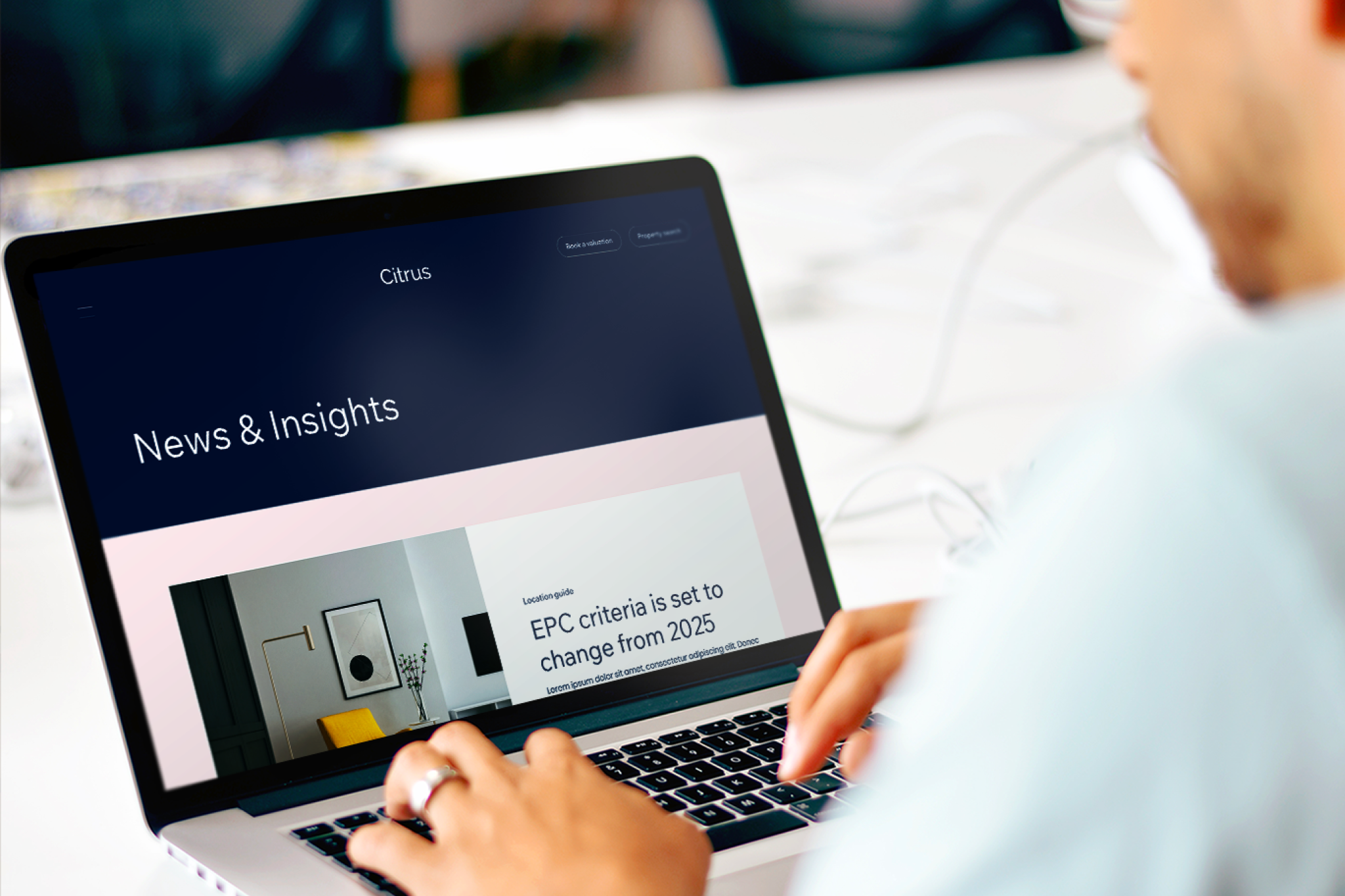 Man with hands on laptop showing News and Insights page on an Estate Agents website